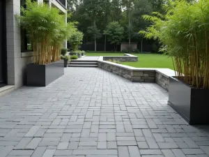 Modern Minimalist Brick Patio - A contemporary brick patio using large-format gray brick pavers in a linear pattern, accented with steel planters containing bamboo, clean lines throughout