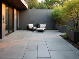 Modern Grey Porcelain Patio - A modern patio with large-format grey porcelain tiles arranged in a clean grid pattern, featuring minimalist outdoor furniture and potted bamboo, photographed in warm evening light