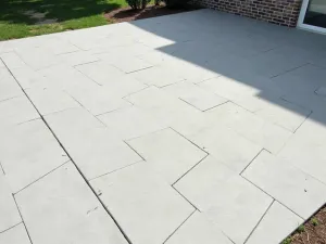 Modern Stamped Concrete Patio - A modern stamped concrete patio with a geometric pattern, showcasing a clean, contemporary design in light gray tones. The surface has a subtle texture and even spacing between pattern elements, photographed in natural daylight