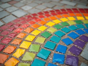 Rainbow Mosaic Effect - Close-up of a patio floor painted to simulate colorful mosaic tiles in a rainbow pattern, with metallic gold grout lines