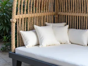 Woven Contemporary Daybed - Close-up of a modern daybed with intricate rope weaving, charcoal frame, and white cushions, set against modern privacy screens