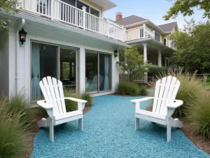 Blue Beach Glass Patio - A coastal-inspired patio with crushed blue beach glass gravel, white Adirondack chairs, rope details, and coastal grasses