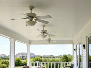 Coastal Fan Light Ensemble - White-ceiling covered patio with multiple white ceiling fans featuring integrated frosted glass light fixtures, overlooking coastal garden