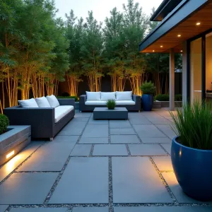 Geometric Twilight Haven - Modern geometric paver patio featuring large-format slate grey stones in an offset pattern. Illuminated by recessed LED perimeter lighting and surrounded by tall ornamental bamboo. Simple modular lounge furniture in charcoal grey with white cushions, accented by blue ceramic planters with dwarf fountain grass.