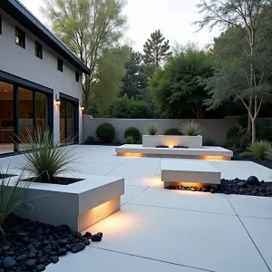 Floating Cube Courtyard - Modern concrete patio featuring suspended cubic concrete platforms with LED underlighting, surrounded by black Mexican river rocks. Minimal plantings of black mondo grass and silver torch cactus in square concrete planters create dramatic contrast against white concrete surfaces