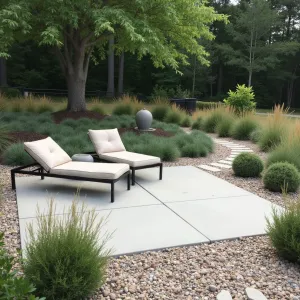 Gravel Border Simplicity - A rectangular concrete patio framed with light gravel borders. Ornamental grasses and Russian sage provide movement and color. Basic metal loungers with removable canvas cushions. Simple concrete sphere water feature creates gentle sound.