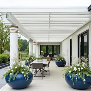 Coastal Breeze Louvered Haven - A sophisticated white alumawood patio cover with adjustable louvers and coastal-inspired posts wrapped in rope details. Surrounded by deep blue ceramic planters featuring White Bird of Paradise, Blue Chalksticks, and Silver Bush Germander, creating a serene seaside atmosphere.