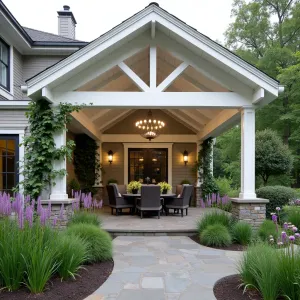 Sunrise Gable Pergola Garden - An elegant gabled alumawood patio cover in pearl white featuring a central skylight panel, bordered by cascading Star Jasmine vines. The structure incorporates built-in LED strip lighting and is complemented by raised beds containing Purple Fountain Grass, Japanese Anemone, and Giant Allium, creating a layered garden effect beneath.