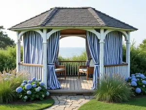 Coastal Style Gazebo - Weathered white wooden gazebo with navy blue striped curtains, surrounded by coastal grasses and hydrangeas