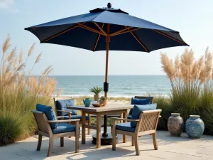 Coastal Tilt Umbrella Deck - Beachy patio setting with a navy blue tilting umbrella, weathered wood furniture, and coastal decor. Ornamental grasses sway in the background